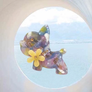 Close-up of bulldog hair clip featuring purple marble acetate finish and yellow flower detail