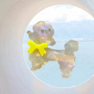 Détail de la pince à cheveux caniche en acétate nacré avec nœud jaune et strass brillants