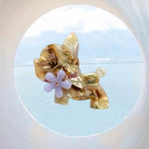 Detail view of acetate french bulldog hair clip with tortoise shell pattern and floral accent