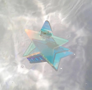Détail d'une pince à cheveux étoile holographique avec reflet sur ondulation d'eau