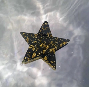 Pince à cheveux étoile en acrylique avec feuille d'or sur fond d'eau scintillante
