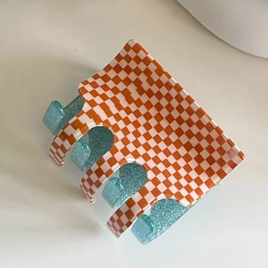 Detail view of the orange checkerboard hair claw clip with blue glitter inner finish