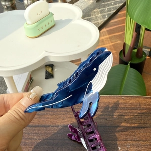 Gros plan sur la pince à cheveux baleine bleue en acétate avec texture nacrée élégante