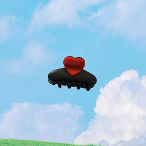Detail der roten Herzverzierung an der schwarzen Haarklammer aus Acetat vor blauem Himmel