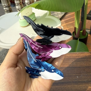 Gros plan détaillé des pinces à cheveux en forme de baleine en acétate noir, violet et bleu