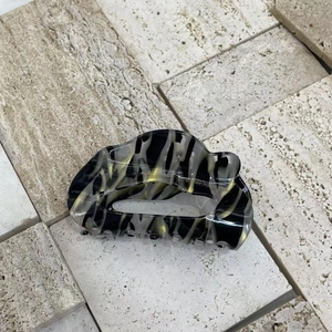 Detailed top view of cloud-shaped acetate hair claw clip with black and gold marble pattern
