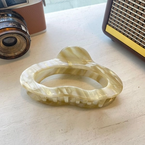 Close-up of cream marble texture acetate hair claw clip with Amy Bear logo detail