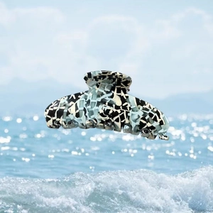 Grande pince à cheveux en acétate avec motif marbre bleu et noir sur fond de mer