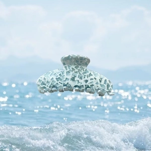 Détail de la pince à cheveux en acétate avec motif craquelé sur l'eau de mer étincelante