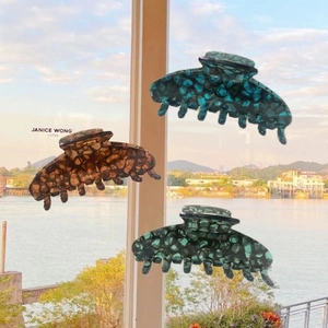 Three acetate hair claws with ink bubble mosaic patterns in blue, amber, and green tones