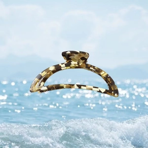 Detail of a half-moon acetate hair claw clip with a classic tortoiseshell pattern design