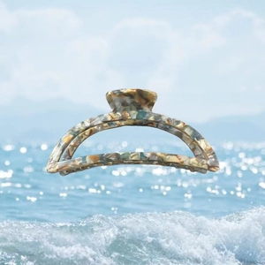 Macro detail of crescent acetate hair claw clip with marble texture over sea background