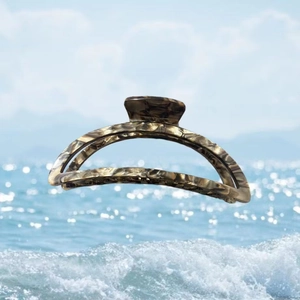 Detail view of acetate claw clip with marble texture over a summer beach background