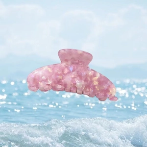 Vue détaillée d'une grande pince à cheveux rose en acétate avec texture nacrée