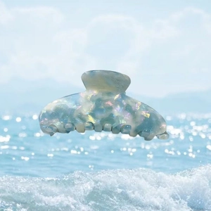 Pince à cheveux en acétate irisé avec texture marbrée bleue sur l'eau de mer scintillante