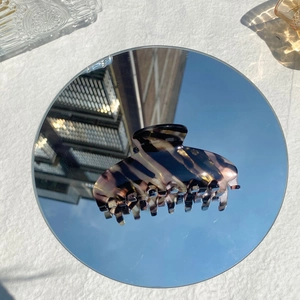 Elegant amber acetate hair claw clip with golden patterns reflecting sky on a mirror surface