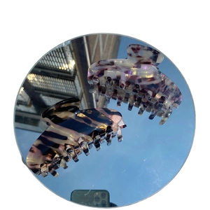 Elegant large acetate claw clips in tortoiseshell and marble purple on mirror surface