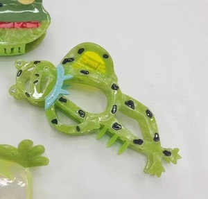 Dettaglio del fermaglio a forma di rana in acetato verde con occhi di cristallo