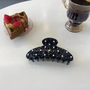 Pince à cheveux élégante en acétate marbré bleu avec perles sur bureau blanc