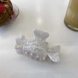 Detail of candy-shaped acetate hair claw with white marble texture on a cafe table