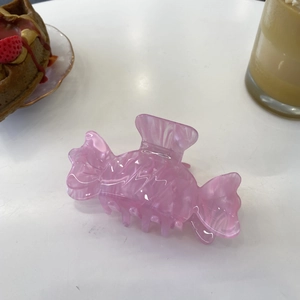 Pink candy-shaped acetate hair claw with marble texture on a white tabletop display