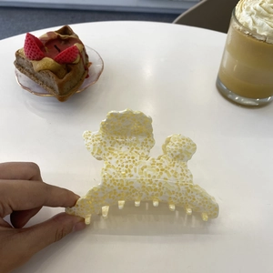 Poodle-shaped acetate hair claw clip shown in a cozy afternoon tea lifestyle setting