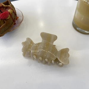 Chic acetate candy-shaped hair claw clip with brown marble texture on white table