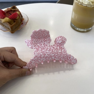 Pink and white spotted poodle hair claw clip held in hand for size reference