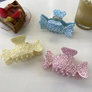 Close-up of candy-shaped acetate hair claws in blue, yellow, and pink with marble texture
