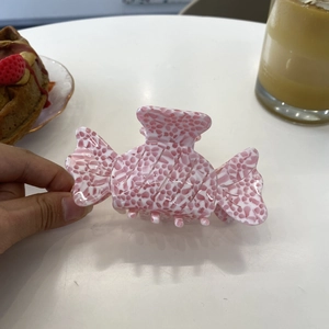 Detail showing the candy-shaped hair claw with pink and white speckled acetate texture