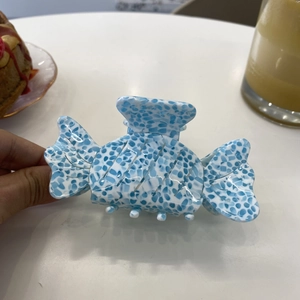 Detail showing candy-shaped acetate hair claw clip with blue and white floral pattern
