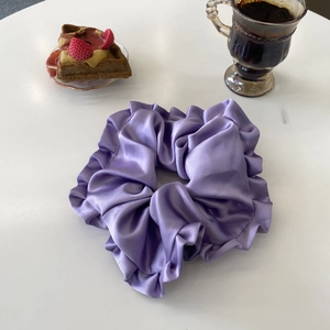 Gros plan d'un chouchou en satin violet à volants dans un décor de thé l'après-midi