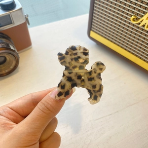 Detailed close-up of a poodle-shaped acetate claw clip in classic tortoiseshell pattern