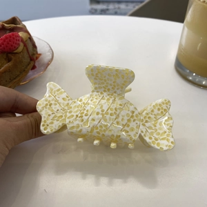 Detail of candy-shaped acetate hair claw clip with yellow and white floral texture
