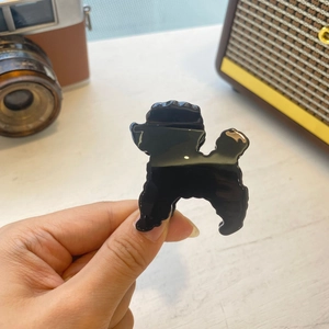 Detail view of the black acetate poodle-shaped hair claw clip held in hand