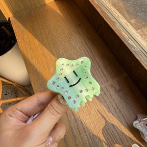 Dettaglio molletta per capelli a stella verde chiaro con strass e simpatico volto sorridente