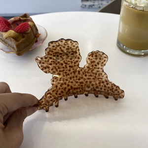 Cute poodle shaped hair claw clip in tortoiseshell acetate being held by a hand