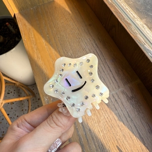 Dettaglio del mollettone a stella in acetato con strass e faccina sotto la luce naturale