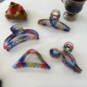 Detail of four large translucent acrylic hair claws with iridescent gradient design