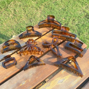 Macro detail of amber tortoiseshell hair claws with metal spring on wood surface