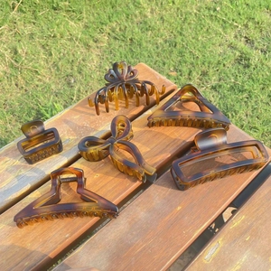 Detailed set of six amber tortoiseshell hair claws in various shapes on a wooden surface