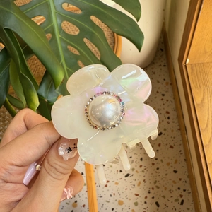 Gros plan sur une pince à cheveux fleur en acétate nacré avec perle et strass multicolores