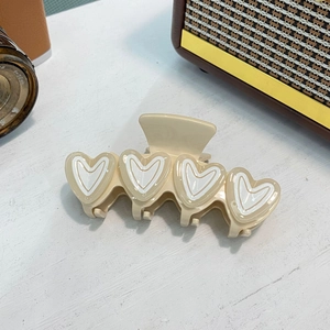 Elegante crèmekleurige haarklem in hartvorm met witte accenten op houten tafel