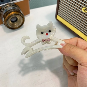 Dettaglio della molletta per capelli a gatto in acetato bianco crema con fiocco rosa