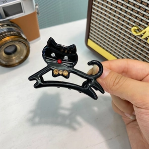 Dettaglio di un fermaglio per capelli a gatto nero in acetato con strass e finitura lucida