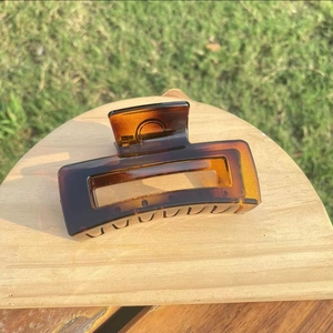 Detailed view of large rectangle tortoiseshell hair claw clip on wooden stand