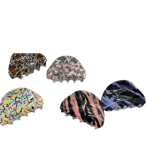 Cinq pinces à cheveux assorties en acétate coloré avec motifs marbrés et rayés sur fond blanc