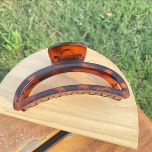 Detail view of large crescent hair claw clip in tortoiseshell resin on wooden tray