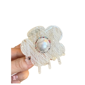 Pince à cheveux fleur en acétate avec perle et strass colorés sur fond blanc neutre