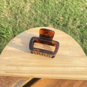 Detailed view of large tortoise shell hair claw clip on a wooden stand